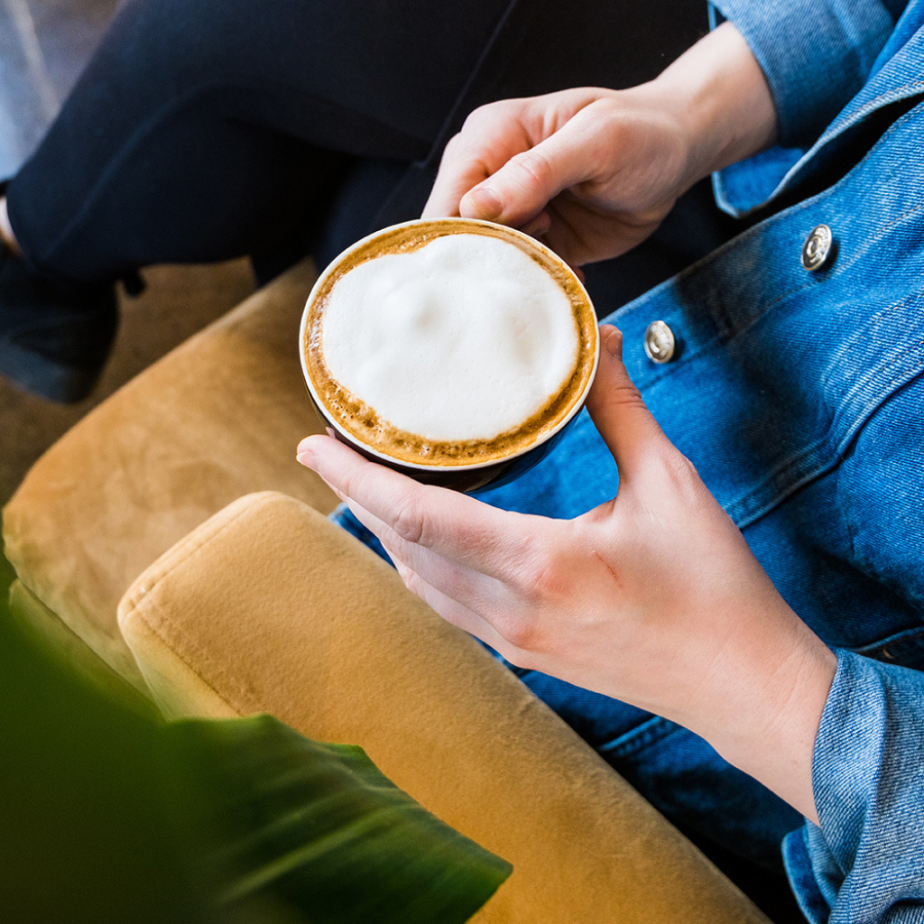 personne sur un fauteill tenant un cappuccino à deux mains